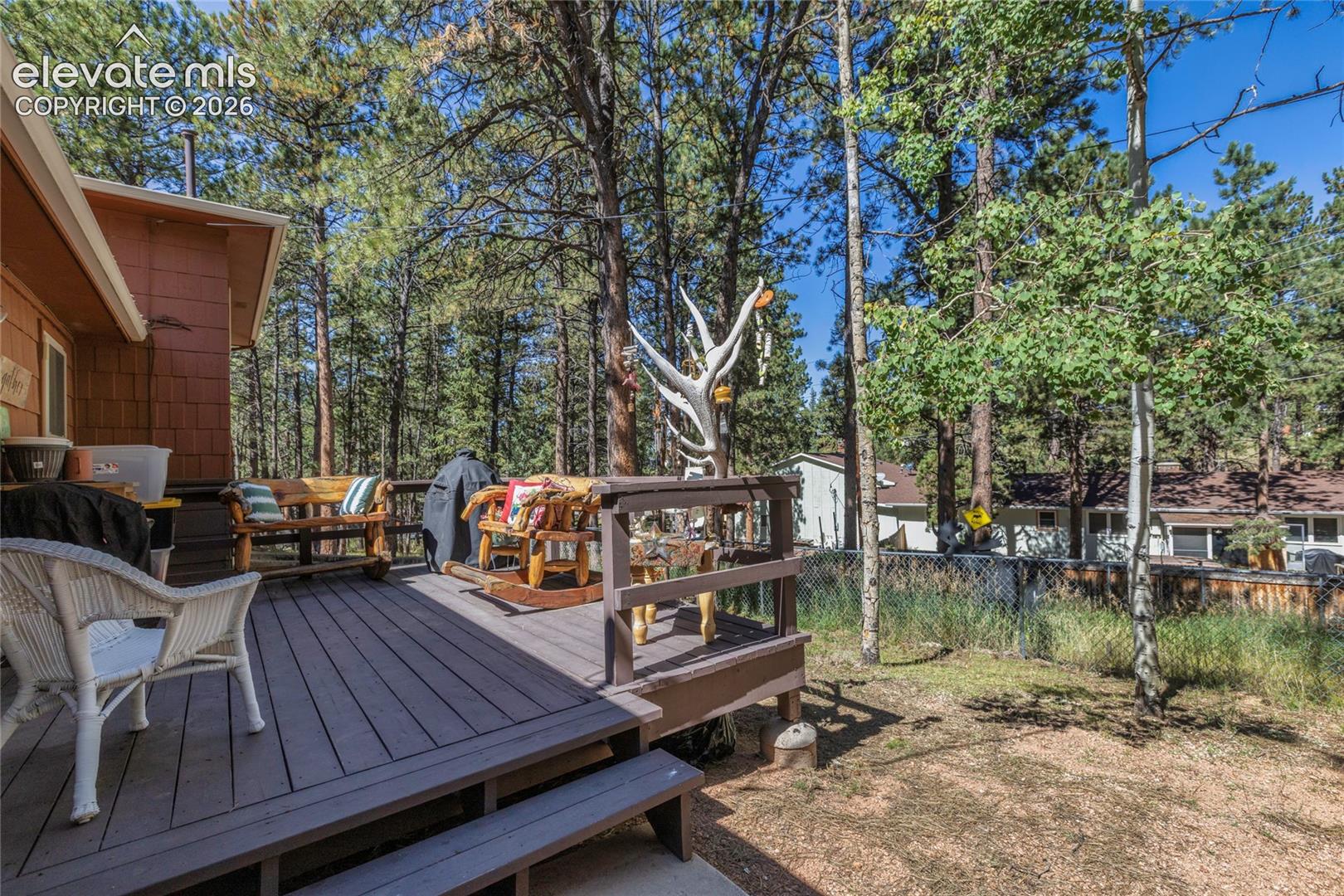 Expansive outdoor deck with composite decking and wood railings, surrounded by mature trees