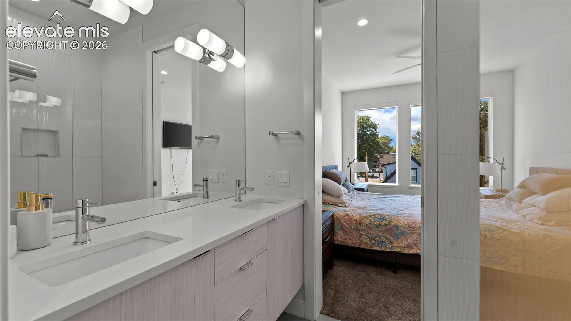 Dual-sink vanity featuring quartz countertops, undermount sinks, polished chrome fixtures, and textured wood-finish cabinetry