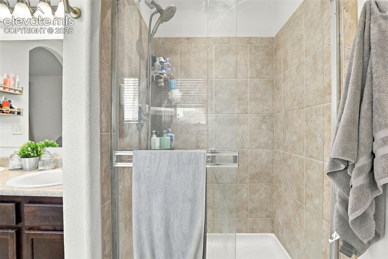Enclosed shower with tiled walls and a white shower pan