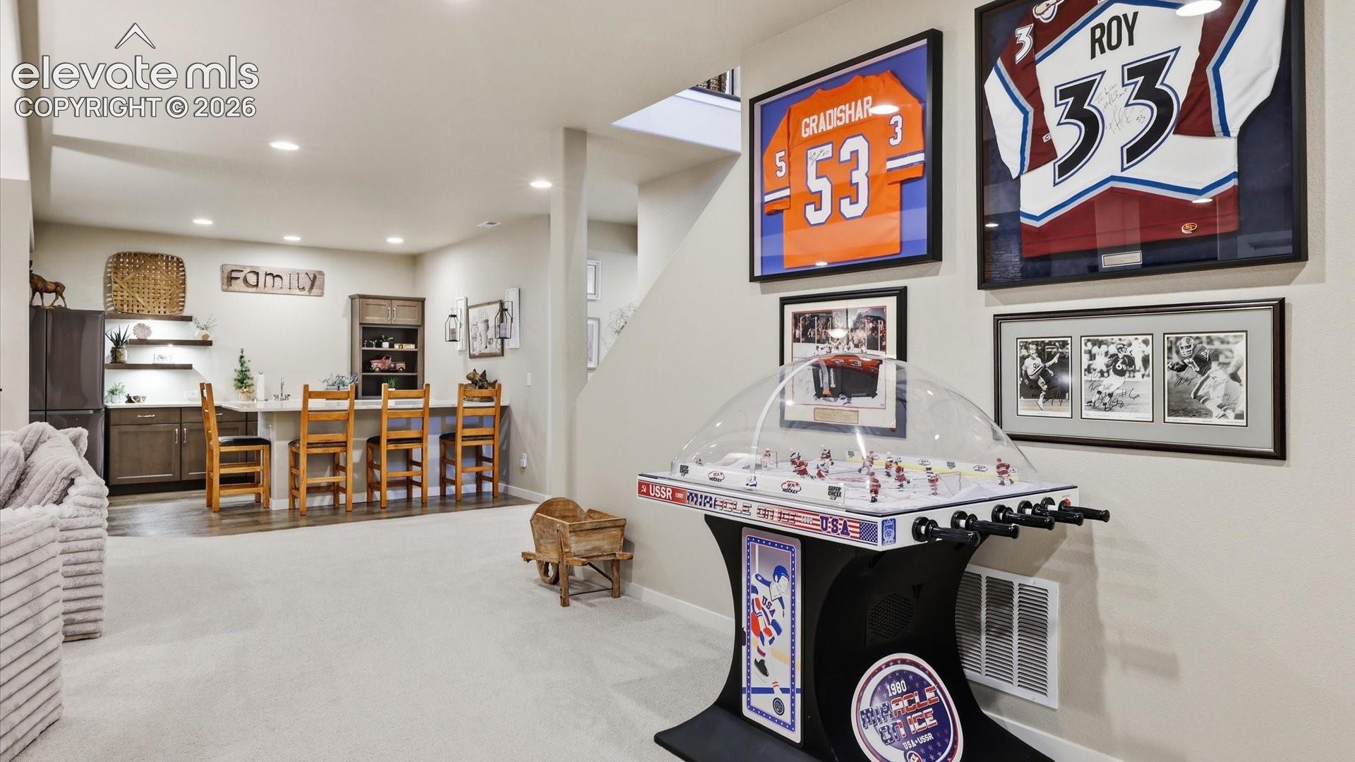 LUXURY LIVING CONTINUES BELOW — A beautifully appointed family room with an adjoining wet bar transforms the lower level into a sophisticated extension of the home’s entertaining spaces.