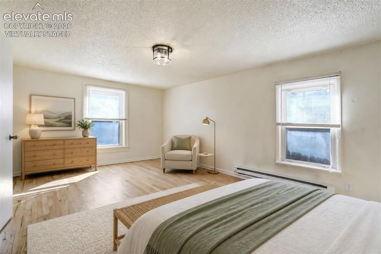 Virtually Staged.  Light-filled room featuring wood-finish flooring, dual windows, and a central flush-mount light fixture