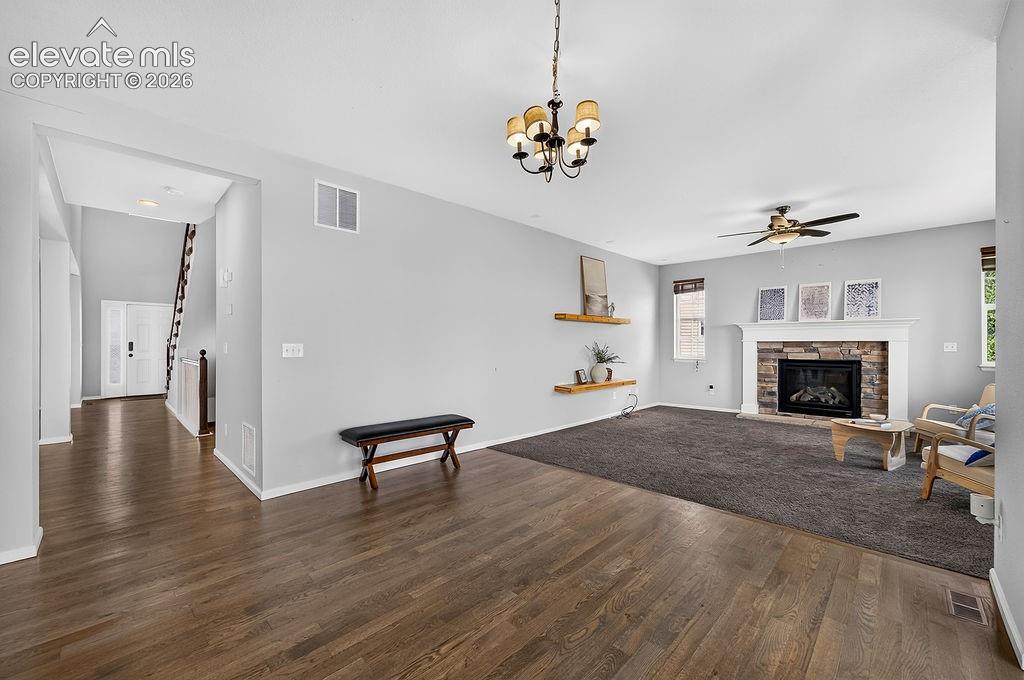 Wood-finish flooring, recessed lighting, ceiling fan, and a fireplace with a stone surround and white mantle