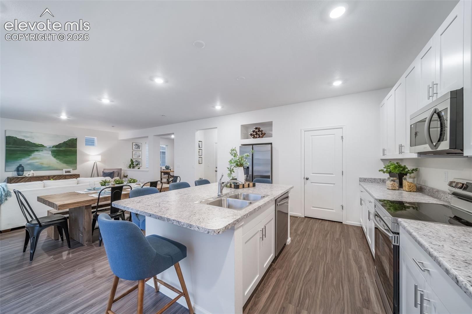 Kitchen featuring white cabinetry, stainless steel appliances, granite-style countertops, wood-finish flooring, and recessed lighting
*photos of a model home*