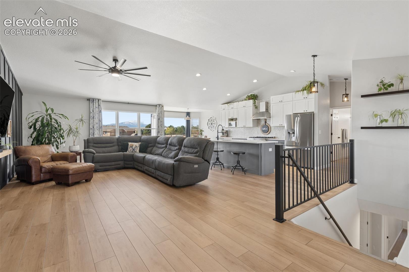 Vaulted ceilings, luxury vinyl flooring, open-concept design, kitchen island with seating, and stainless steel appliances