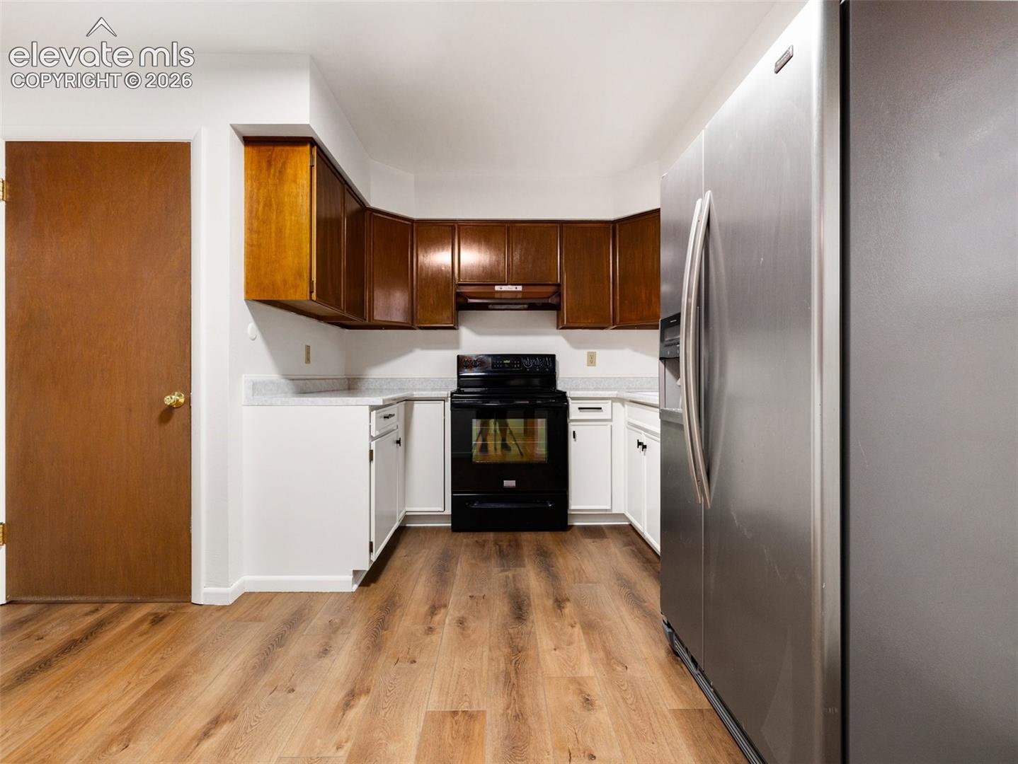Wood-finish flooring with white base cabinetry, complemented by dark wood upper cabinetry