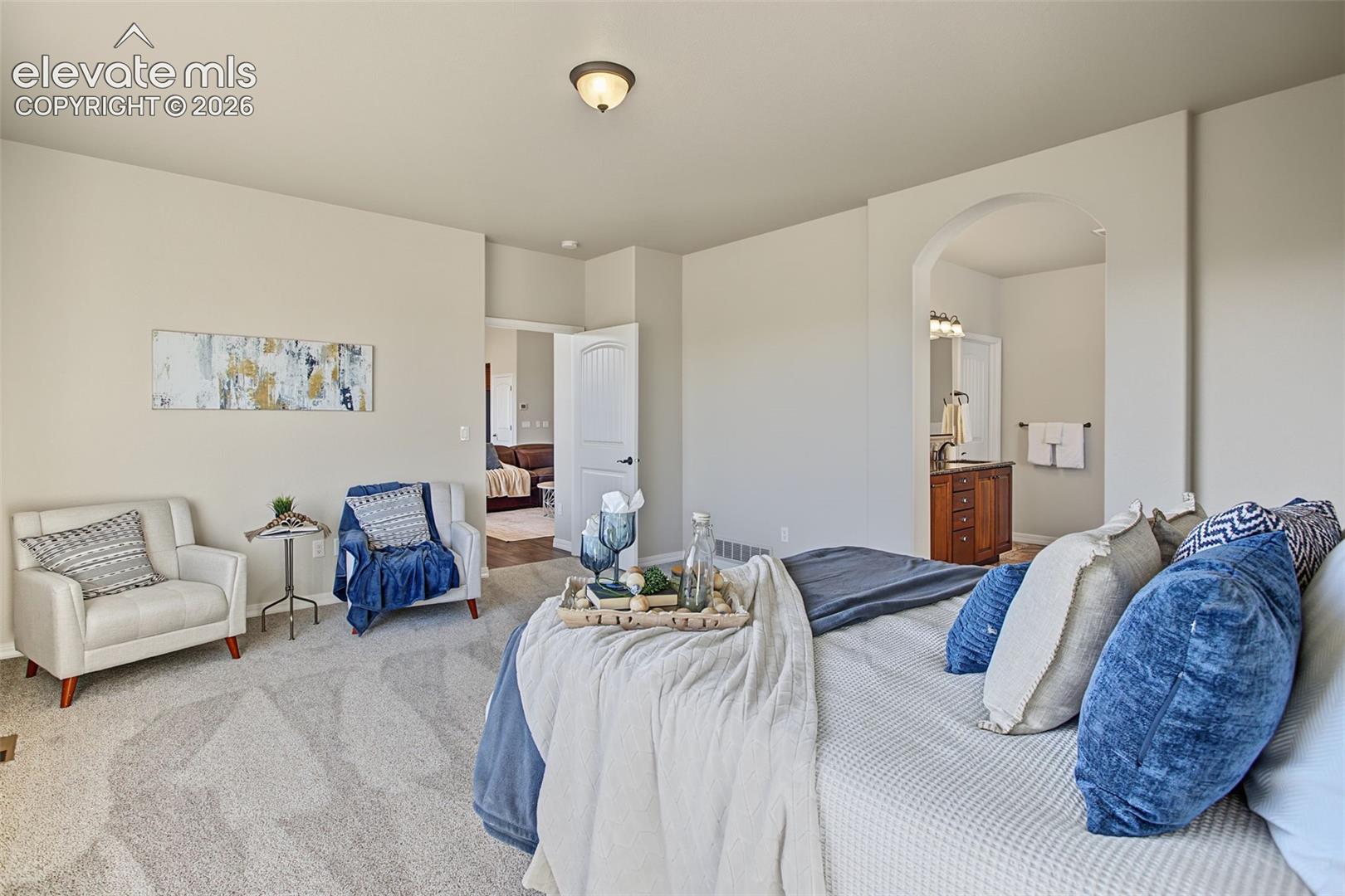 Neutral-toned carpeted interior featuring arched entryway detailing, solid-core interior doors, and a built-in wooden vanity with dual-light fixture
