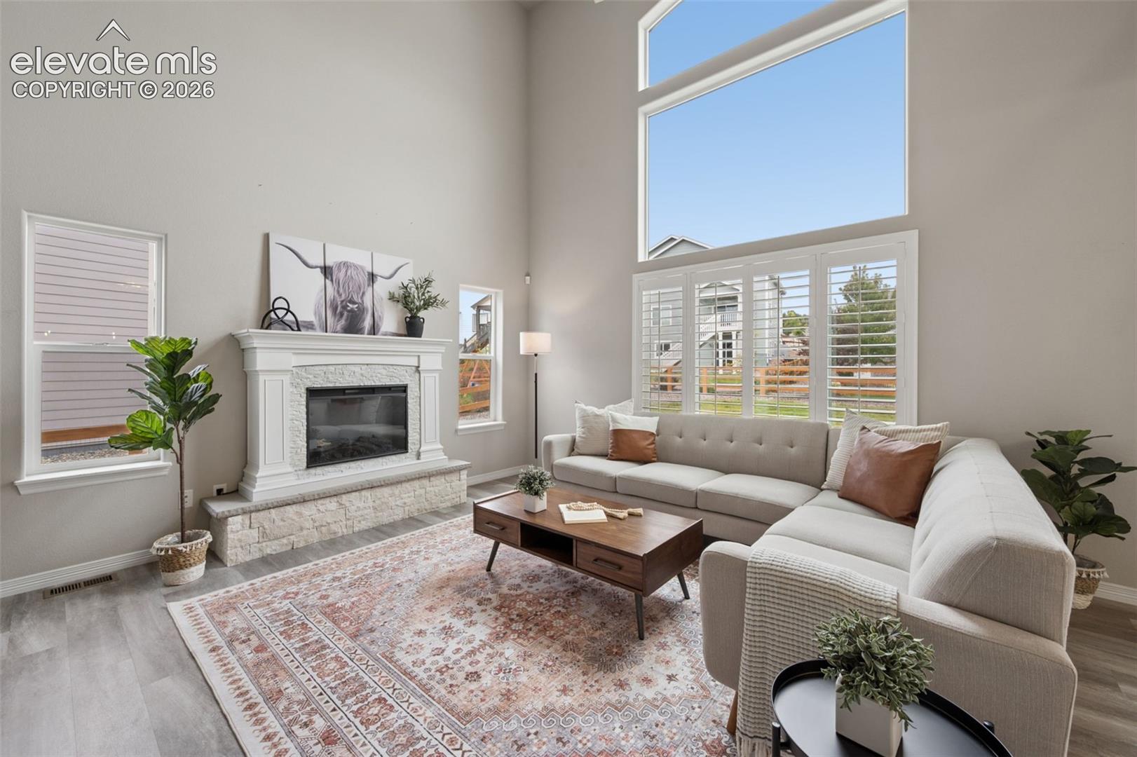 Vaulted ceilings, a built-in fireplace with a stone surround, and wood-finish flooring