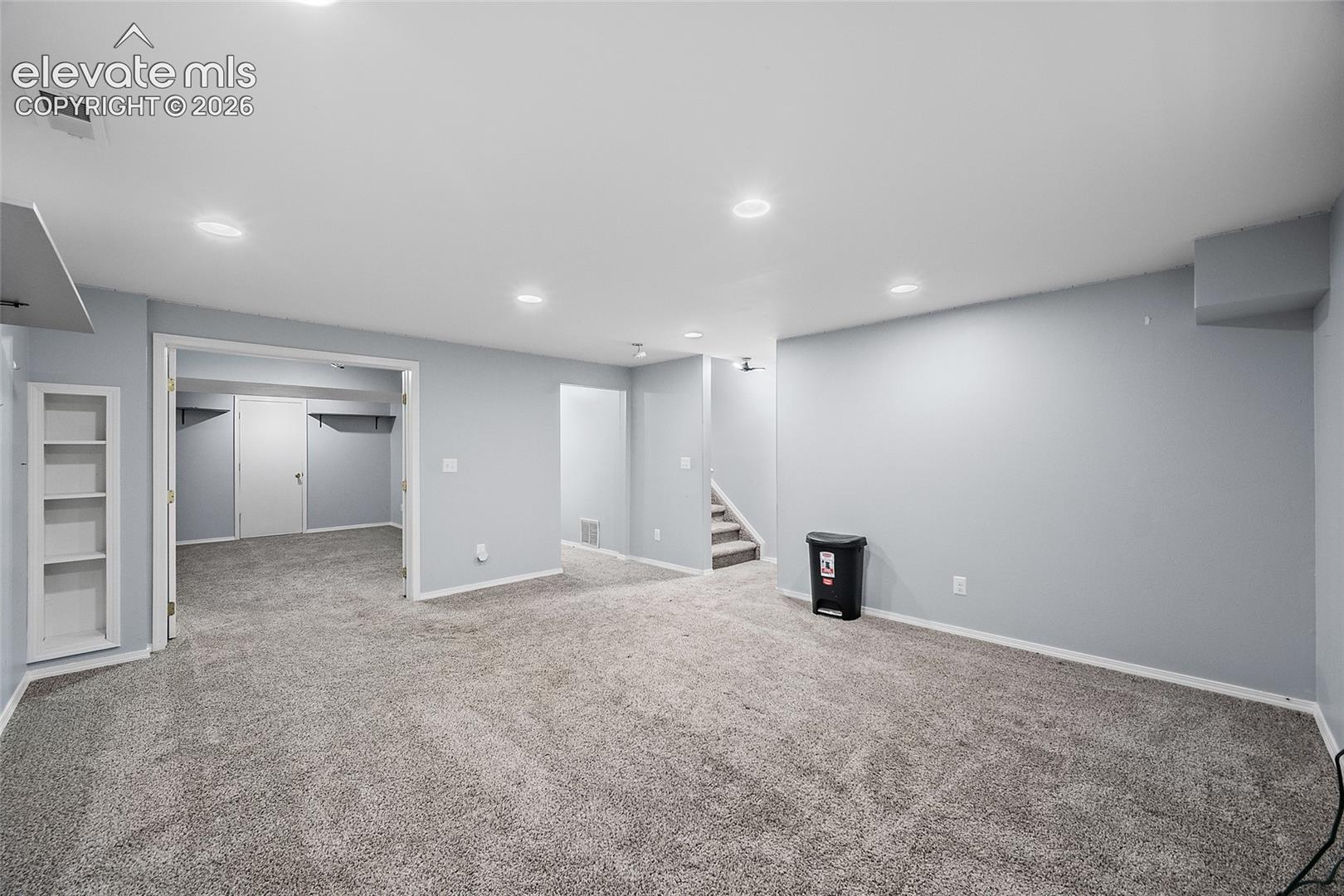 Spacious room with gray wall paint, recessed lighting, and built-in shelving