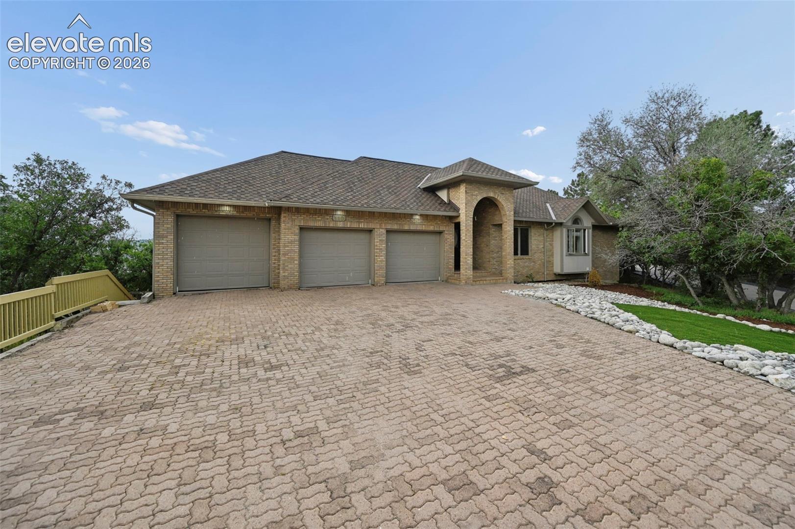 Brick exterior featuring a three-car garage and a paved driveway