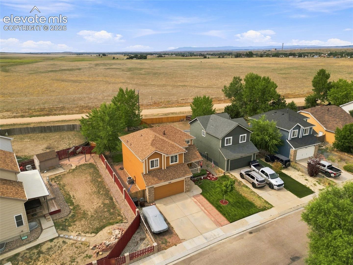 Two-story residence with a two-car garage, fenced backyard, and mature trees