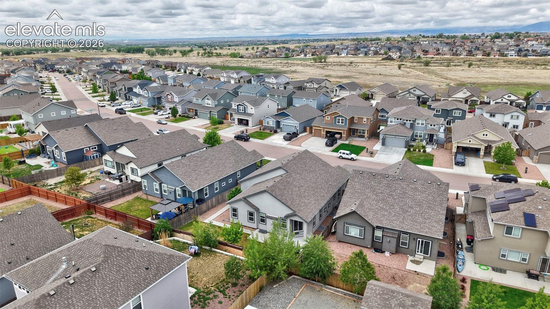 Aerial perspective of a suburban neighborhood featuring paved streets, attached garages, diverse roof pitches, and established landscaping