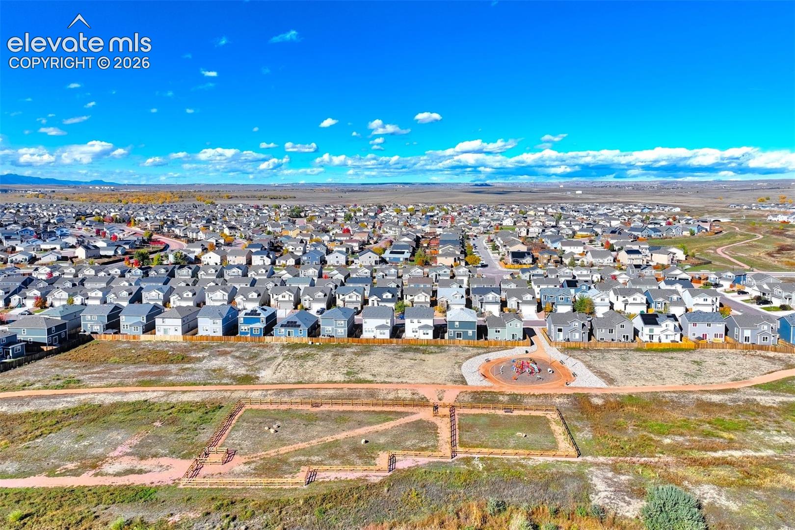 Aerial perspective of residential area featuring integrated walking paths and a circular playground facility
