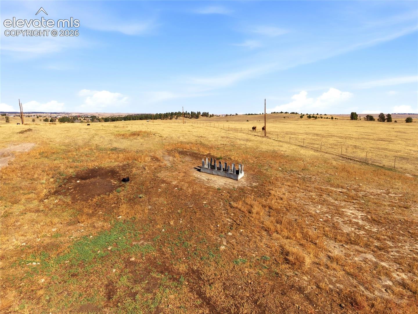 Expansive acreage featuring wire fencing and a metal livestock feeder
