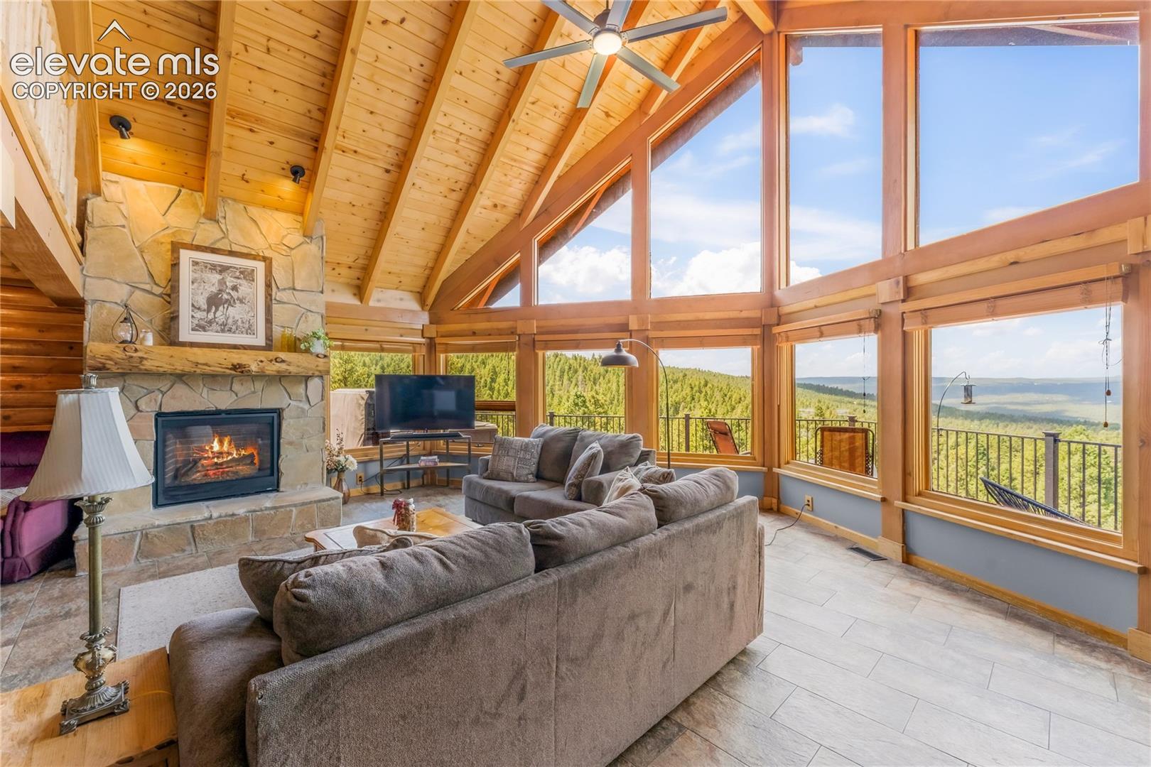 Vaulted wood-paneled ceilings, a stone-clad fireplace, and extensive window walls with wood framing