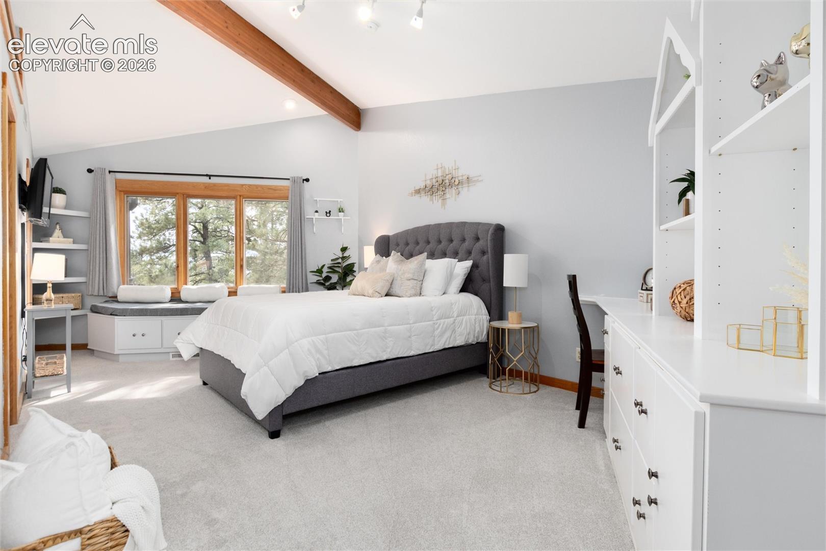 Spacious bedroom with sitting bench in front of window 