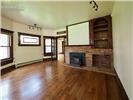Wood-finish flooring, masonry fireplace with integrated hearth, built-in wooden shelving, dark-stained window casings, and multi-pane glass doors
