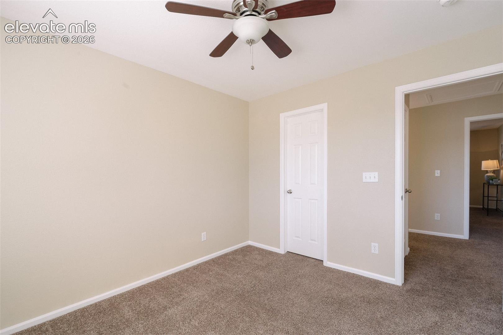 Neutral wall finishes, textured carpeting, and a ceiling-mounted fan with integrated lighting