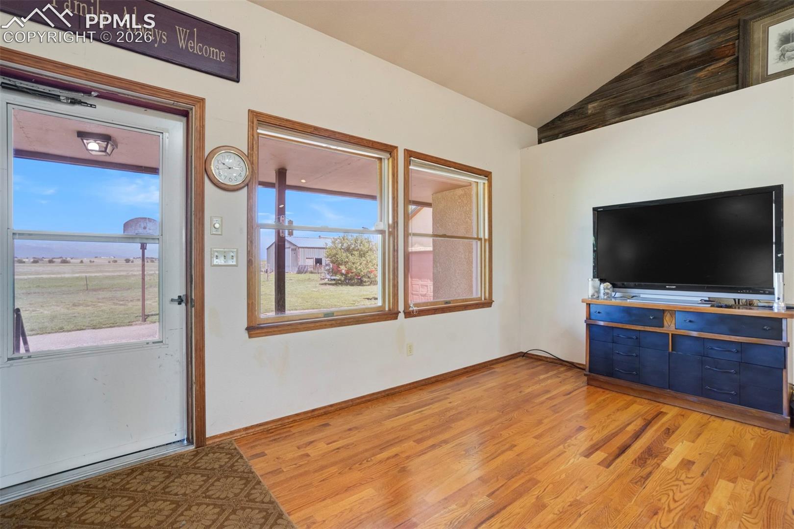 Hardwood flooring extends throughout the living area, featuring a vaulted ceiling with wood accents