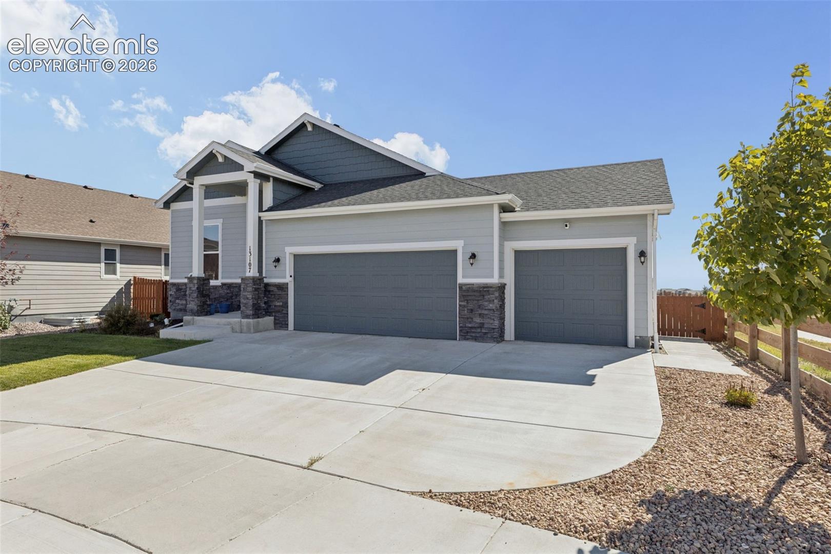 Exterior featuring horizontal lap siding, stacked stone veneer accents, a three-car garage, and a concrete driveway