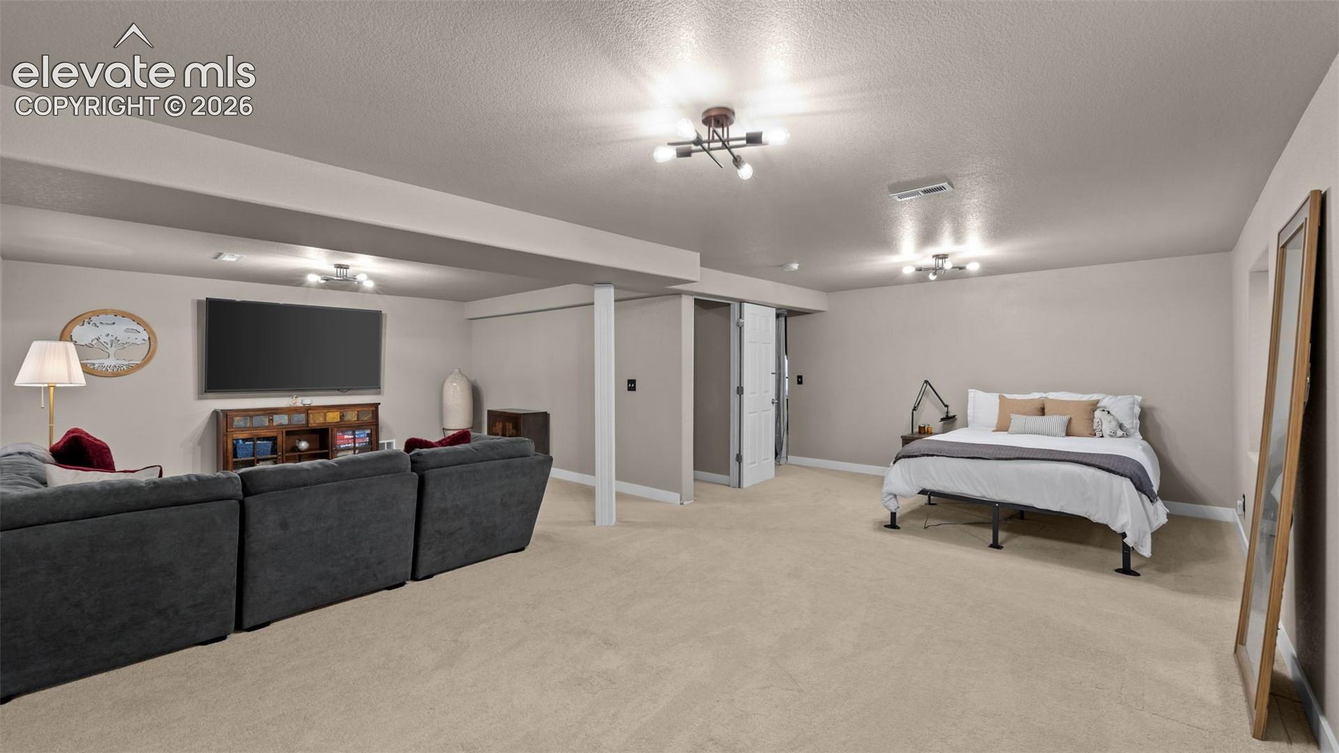 Neutral-toned interior space featuring wall-to-wall carpeting, recessed and multi-arm ceiling-mounted lighting, and a support column