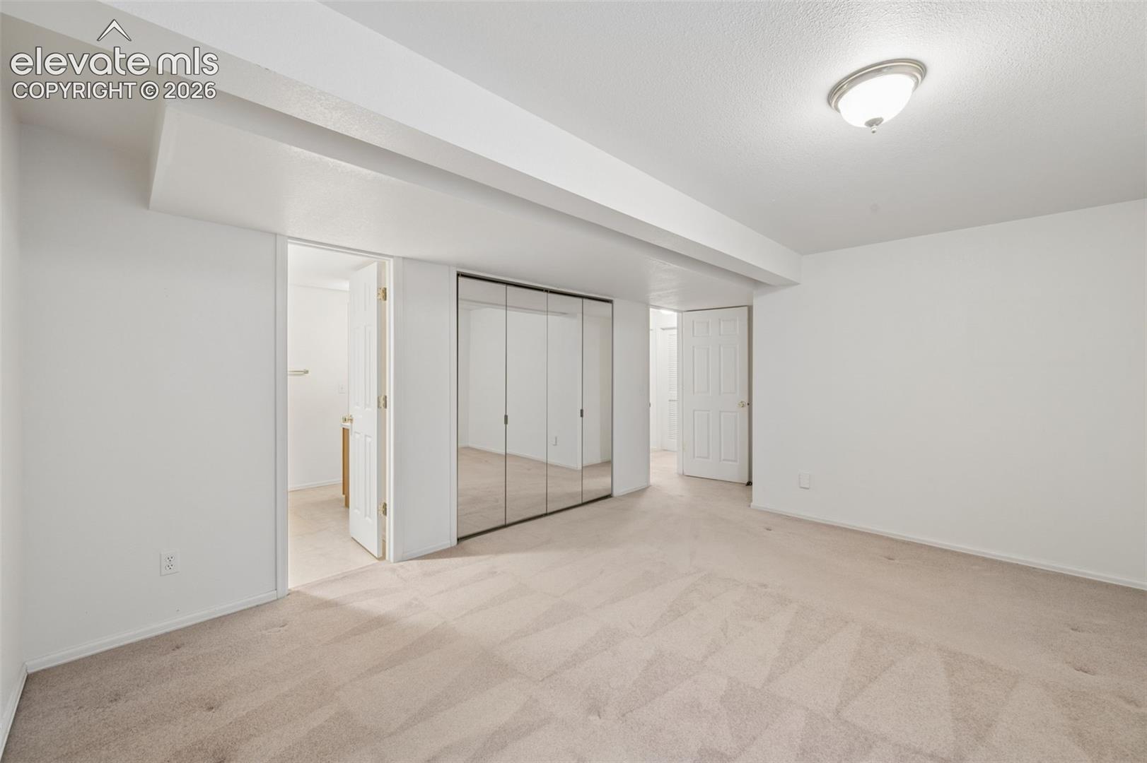 Neutral-toned carpeting, mirrored sliding-door closet, flush-mount ceiling lighting, and solid-core interior doors