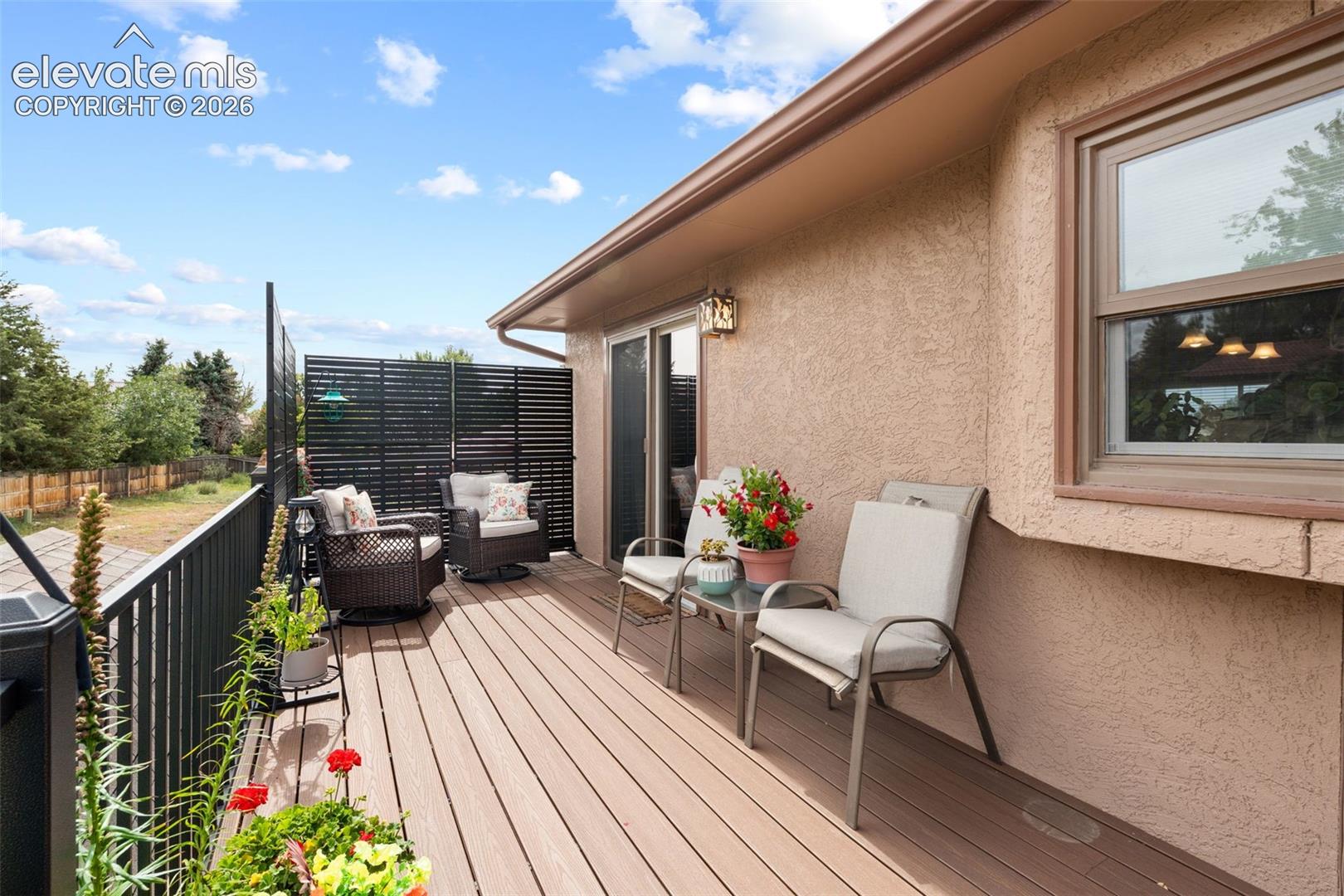 Elevated deck featuring composite decking, black metal railings, and a privacy screen