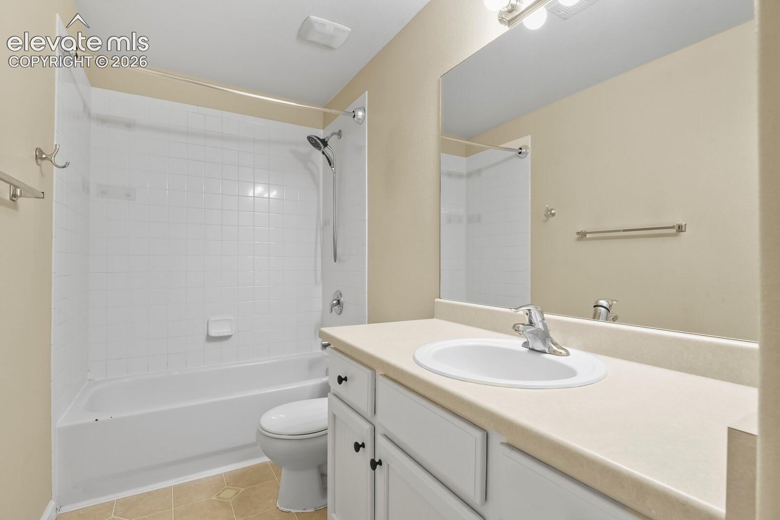 Bathroom featuring a white vanity with an integrated sink, a large wall-mounted mirror, and a full-size tub with white subway tile surround
