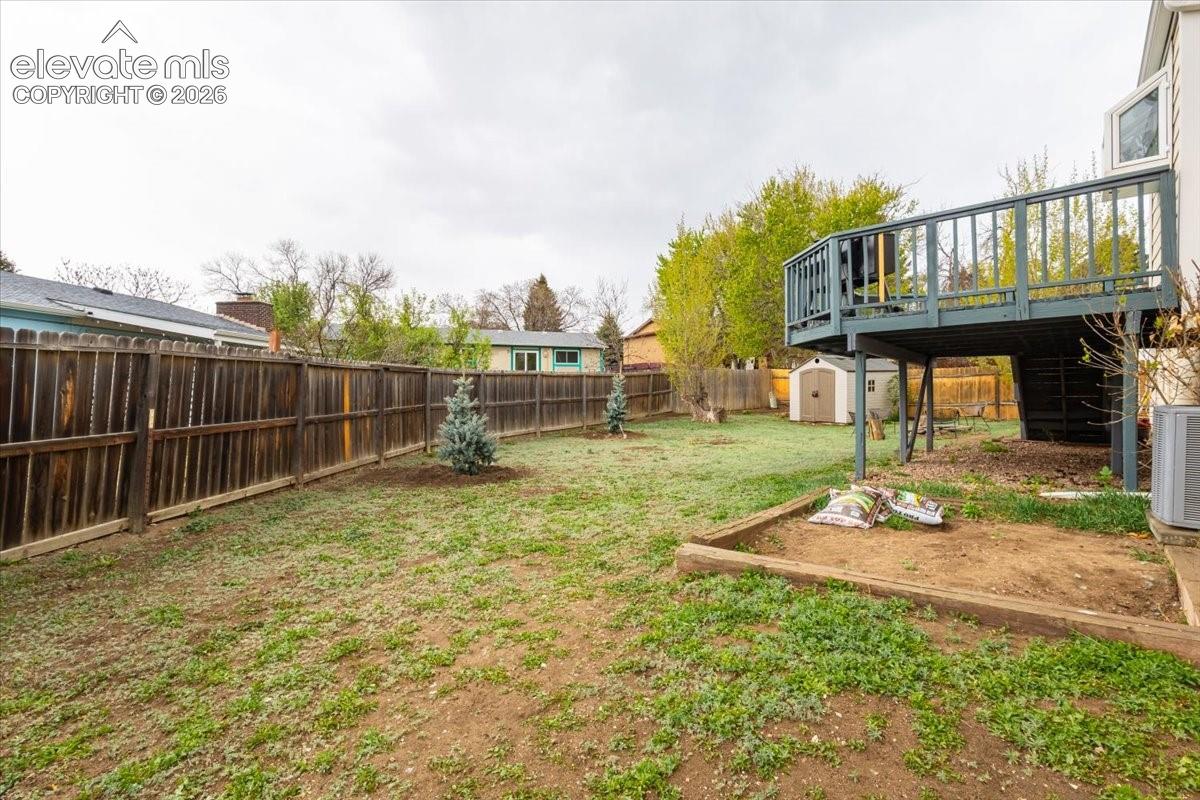 Expansive backyard featuring a wood fence, established trees, and a raised wooden deck