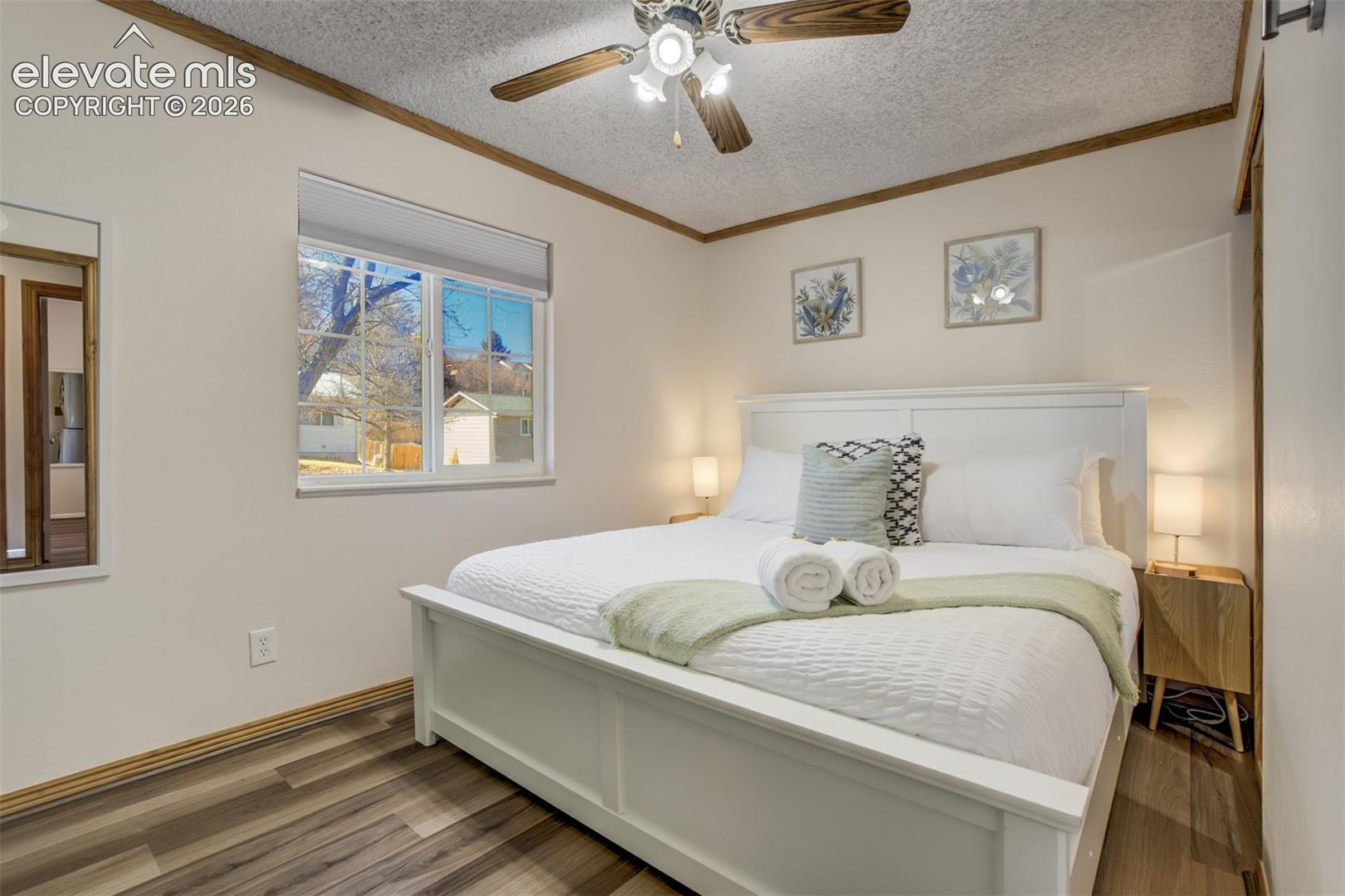 Recessed lighting, wood-finish flooring, ceiling fan, white window trim, and a window opening to another room