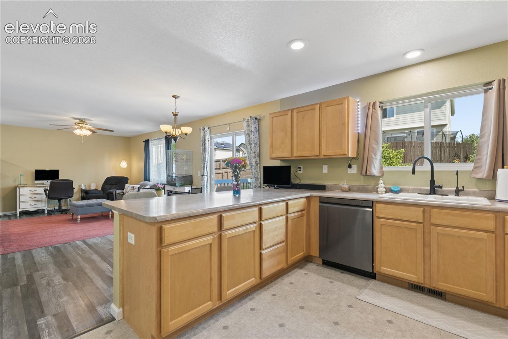 Open-concept kitchen with light wood cabinetry, a stainless steel dishwasher, and a black gooseneck faucet