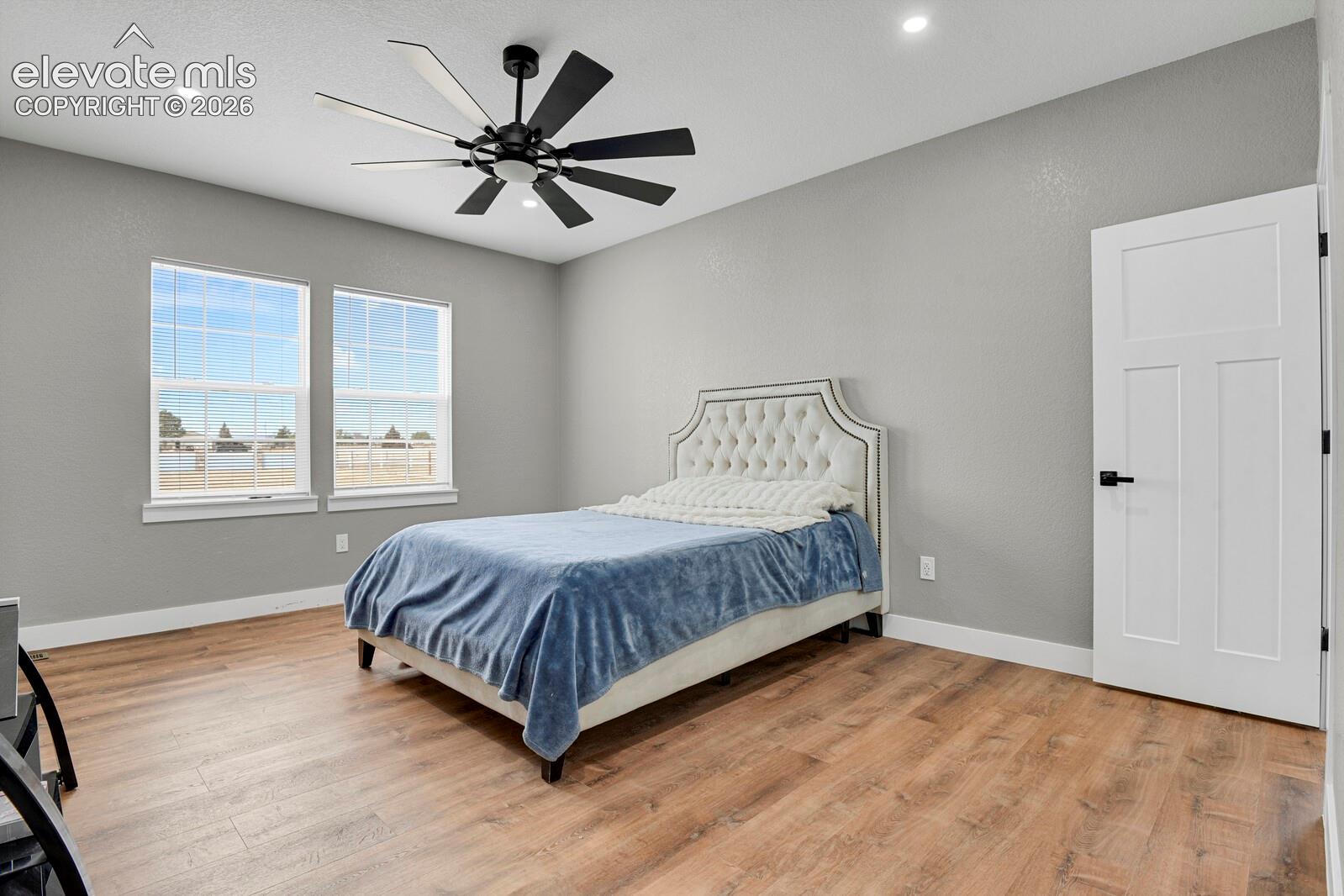 Recessed ceiling lighting, wood-finish flooring, and a modern ceiling fan with multiple blades