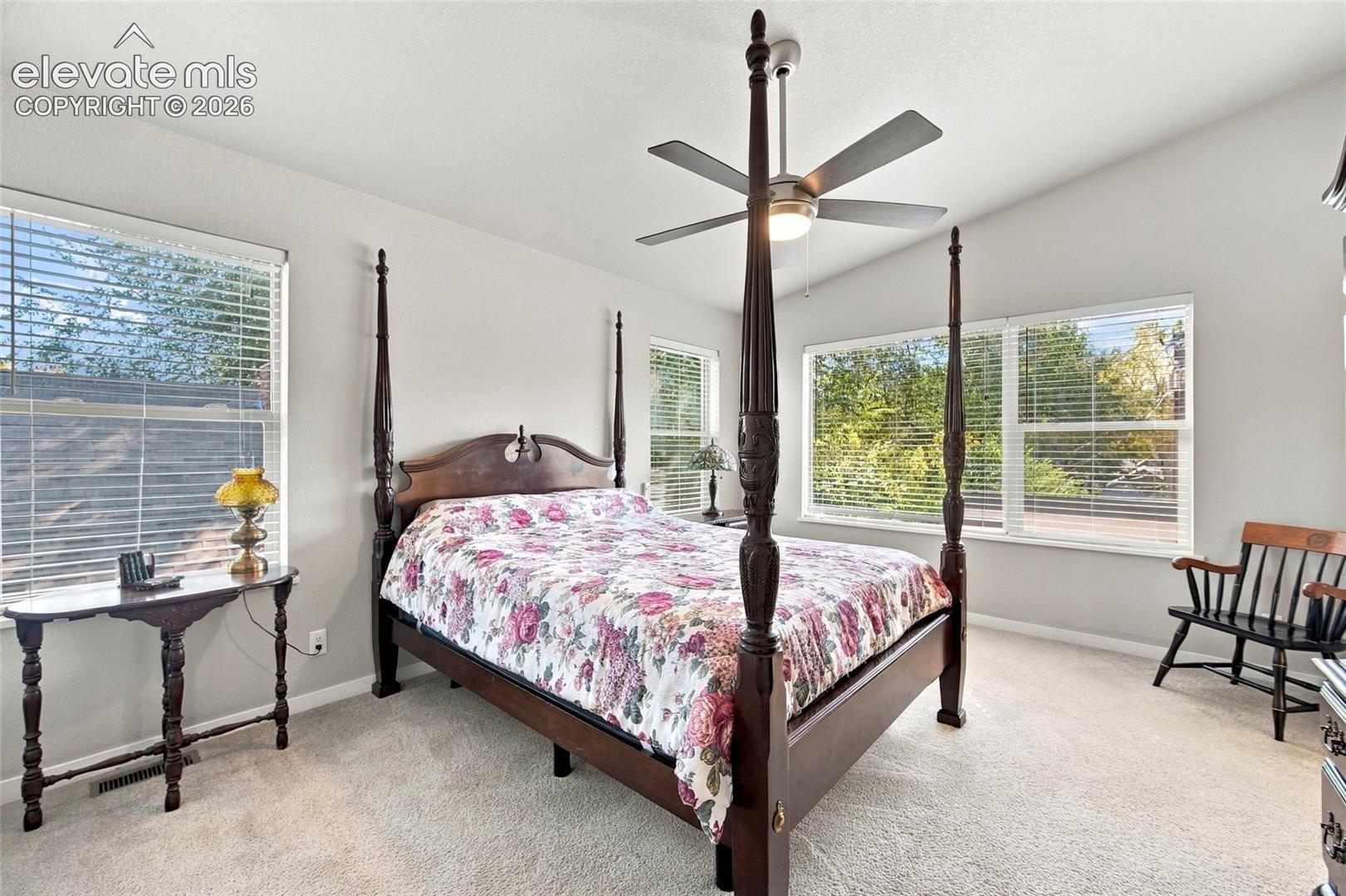 Vaulted ceiling featuring a central brushed-nickel ceiling fan with integrated lighting and large windows with horizontal blinds