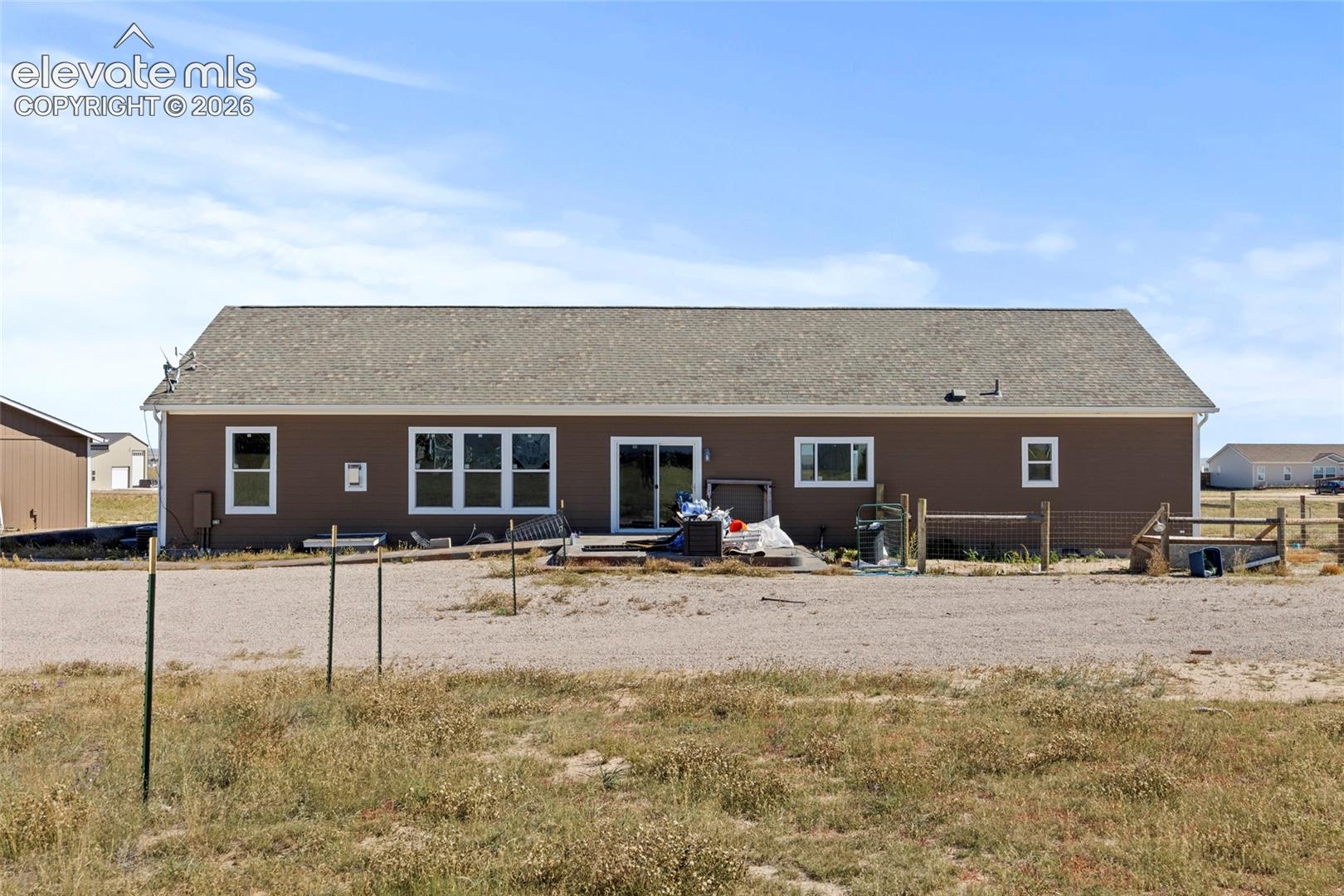 Rear exterior elevation featuring horizontal siding, asphalt shingle roofing, glass sliding doors, and rectangular windows