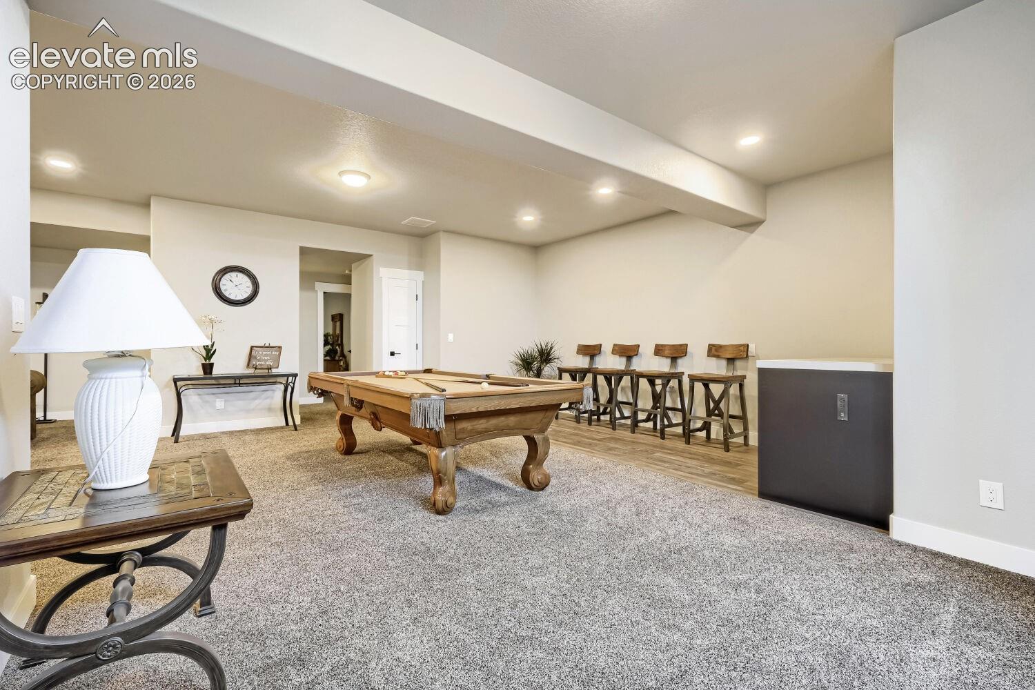 Recessed lighting, light-toned walls, and carpet flooring create a versatile space