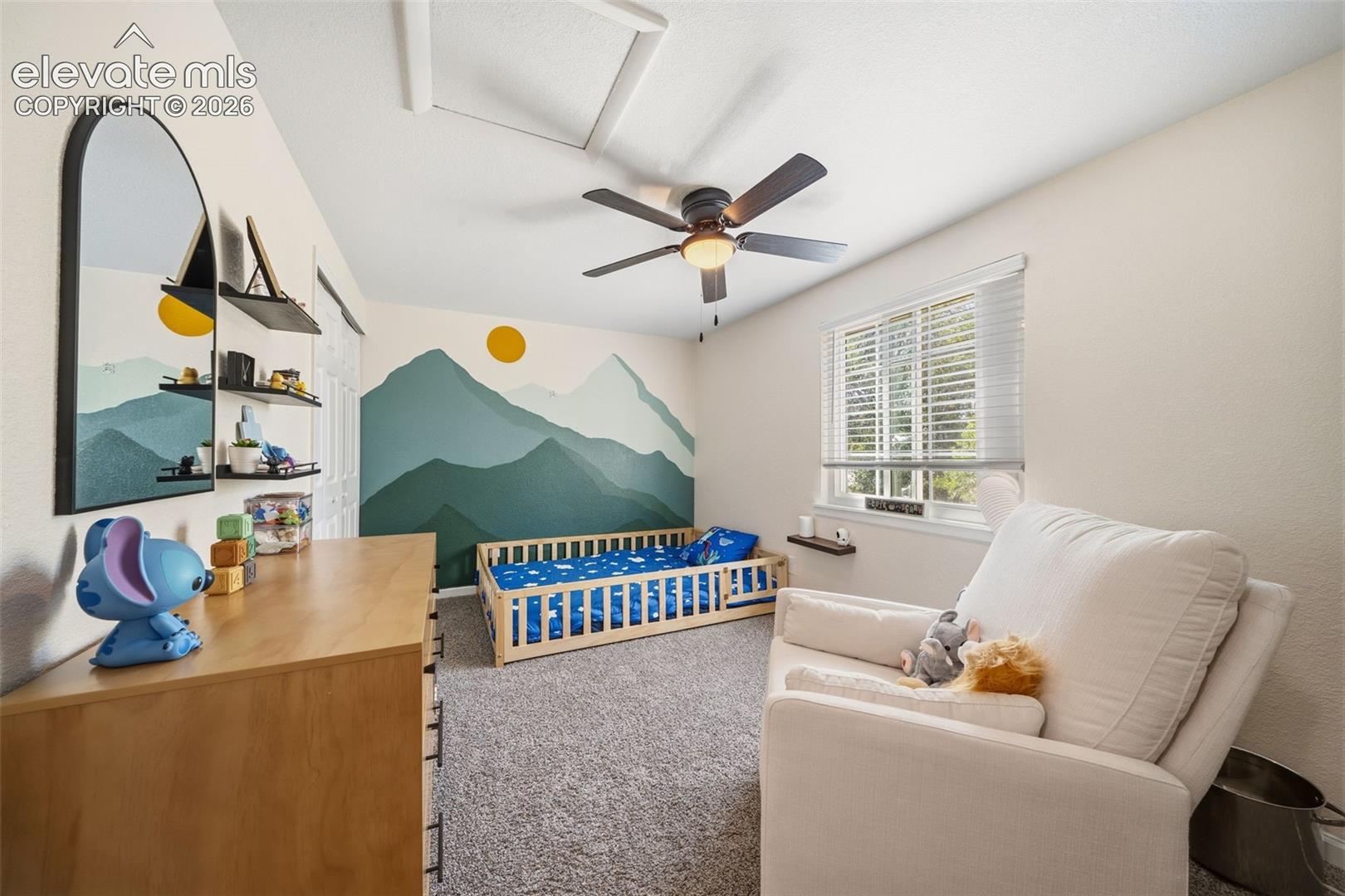 Recessed lighting, ceiling fan with light fixture, window with blinds, wall-mounted shelving, and gray carpet flooring