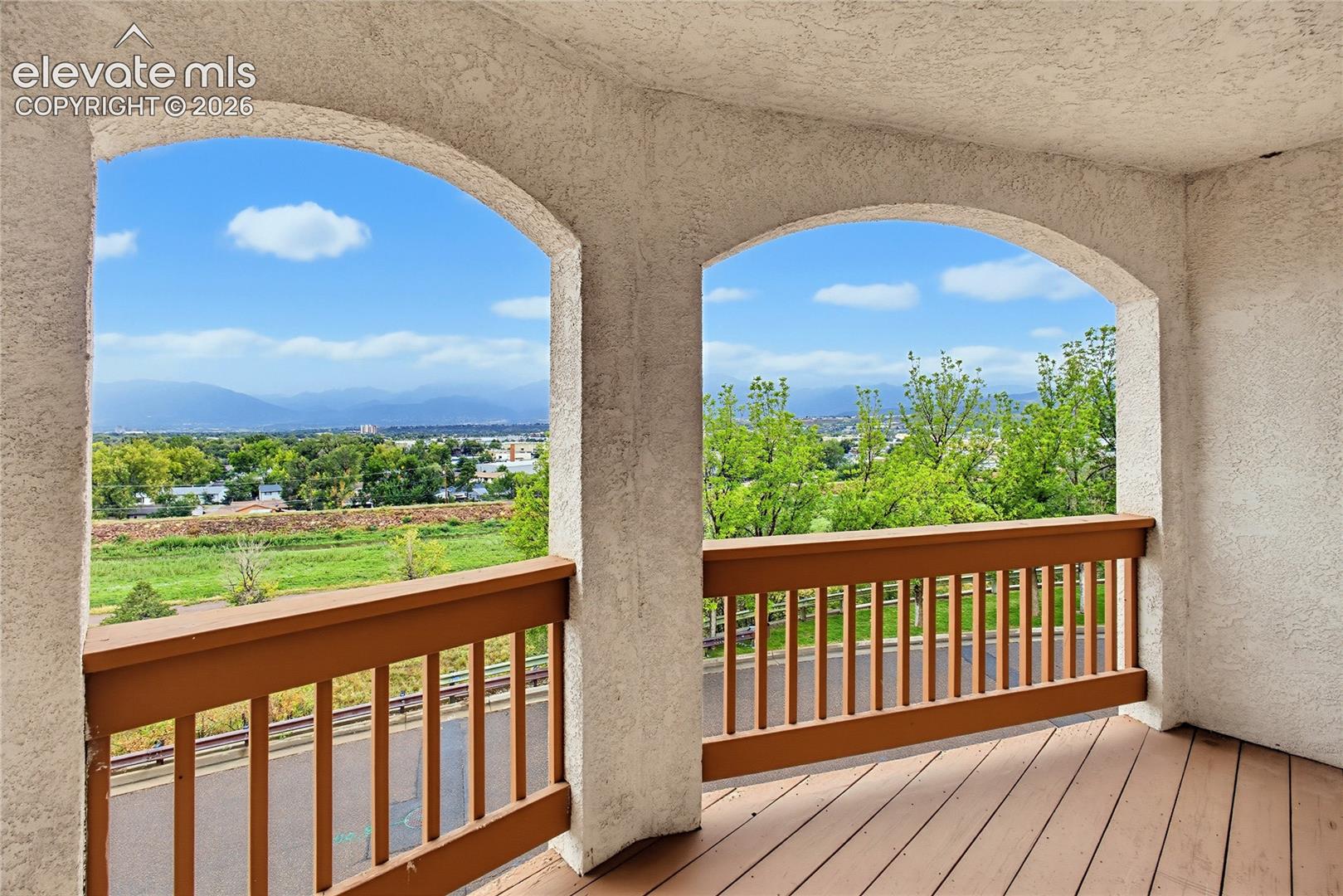 Arched balcony openings with a natural wood-finish railing and decking