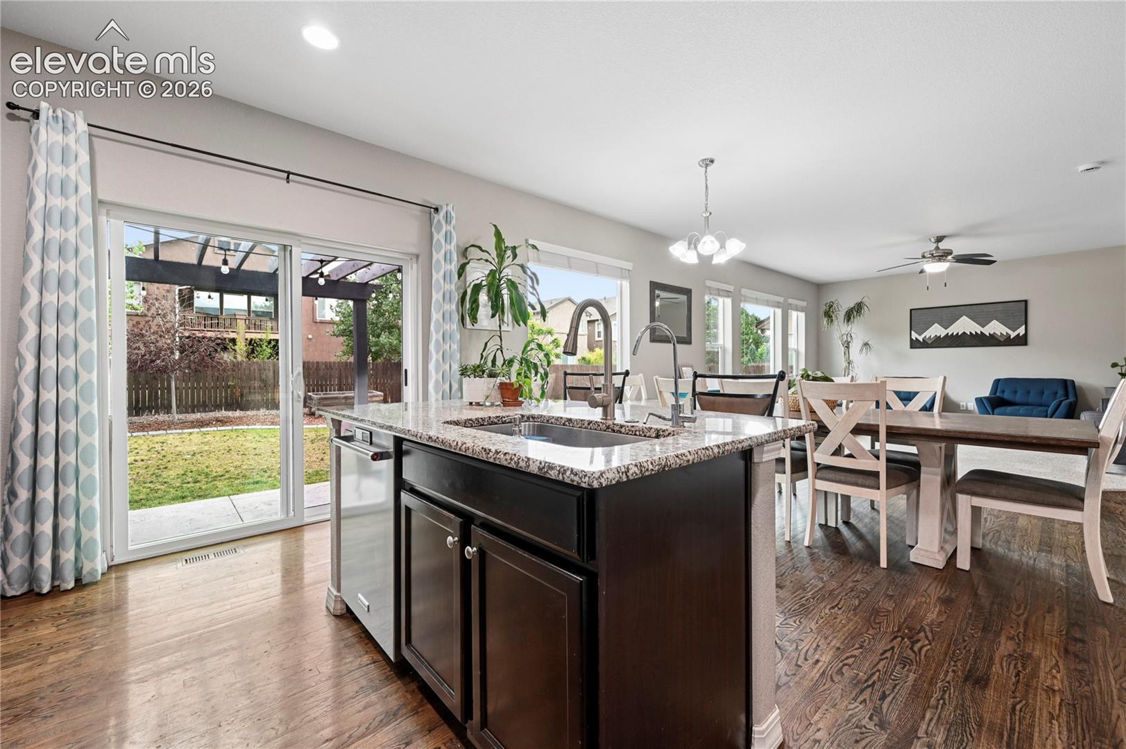The kitchen island with its farmhouse sink and granite counters doubles as a breakfast bar with extra continuous counter space, and the open main-level rooms are bright, connected, and all just the right size.