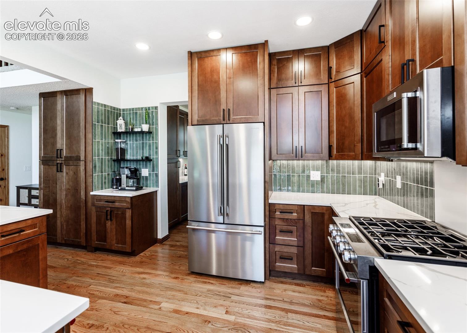 Wood-finish flooring, stainless steel appliances, custom cabinetry, quartz countertops, and a unique tile backsplash