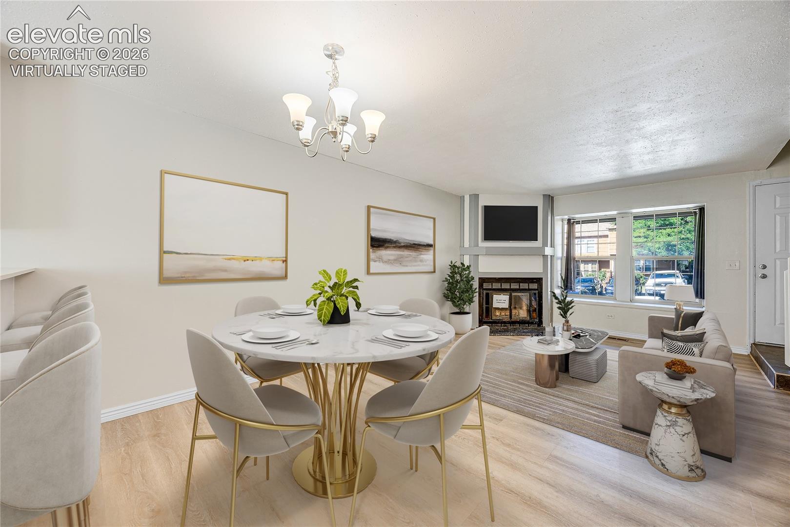 virtually staged
Open-concept living area featuring wood-finish flooring, a white fireplace with a dark insert, and multiple windows