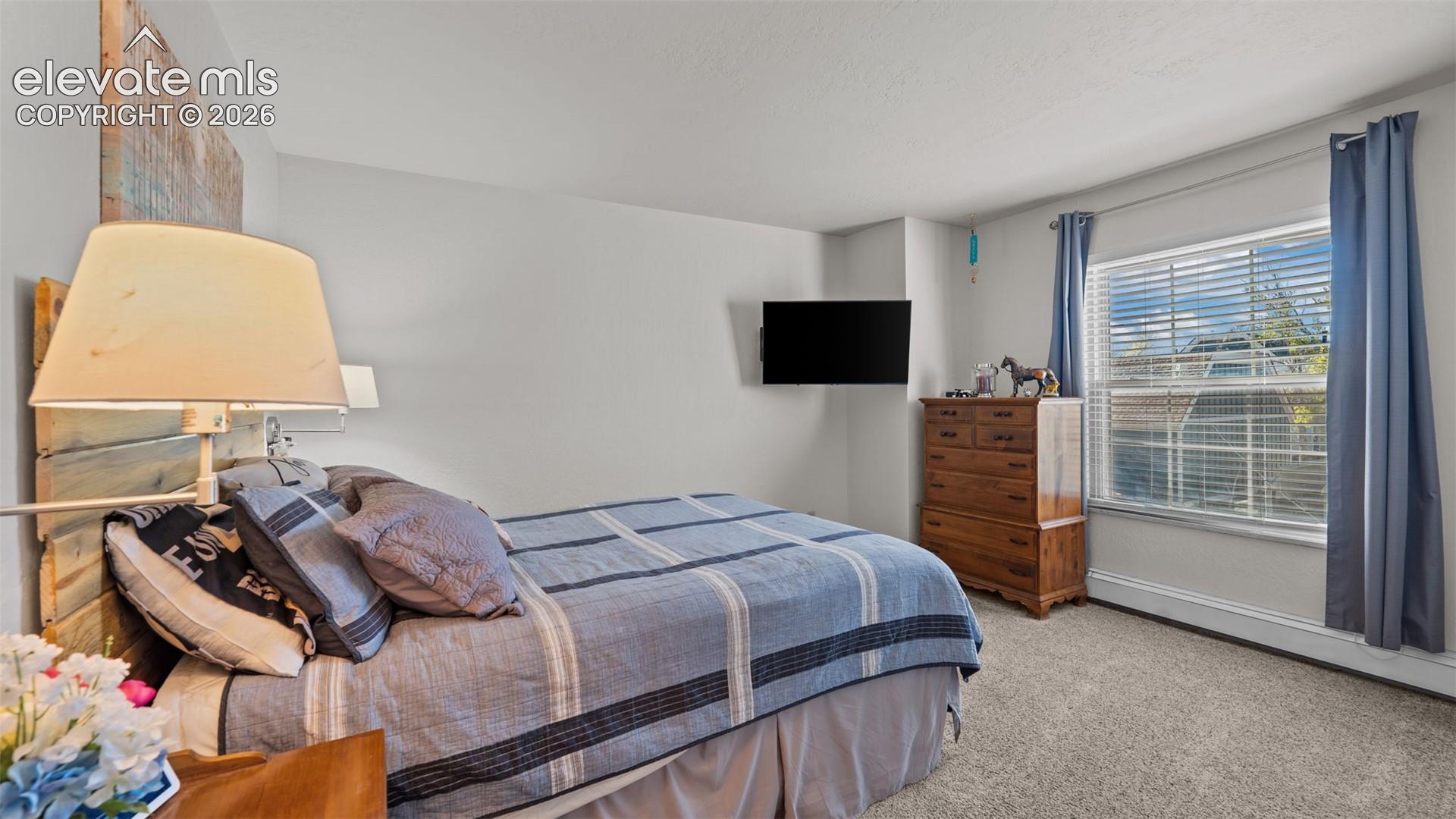 Neutral-toned interior featuring wall-to-wall carpeting and a single-pane window with horizontal blinds