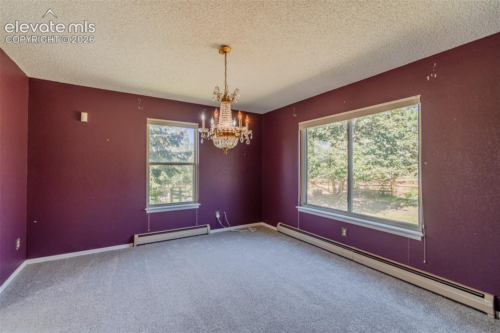 Room featuring two windows, carpeted flooring, and a decorative chandelier