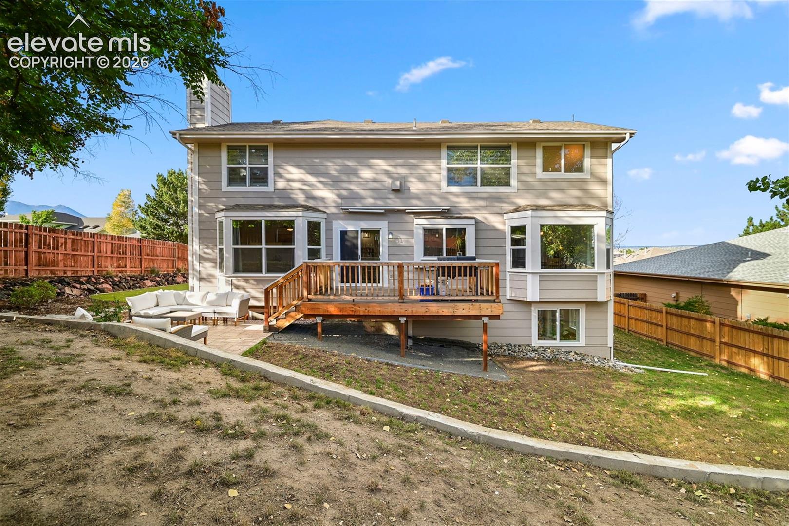 Expansive backyard featuring a wood deck, a flagstone patio, and a privacy fence