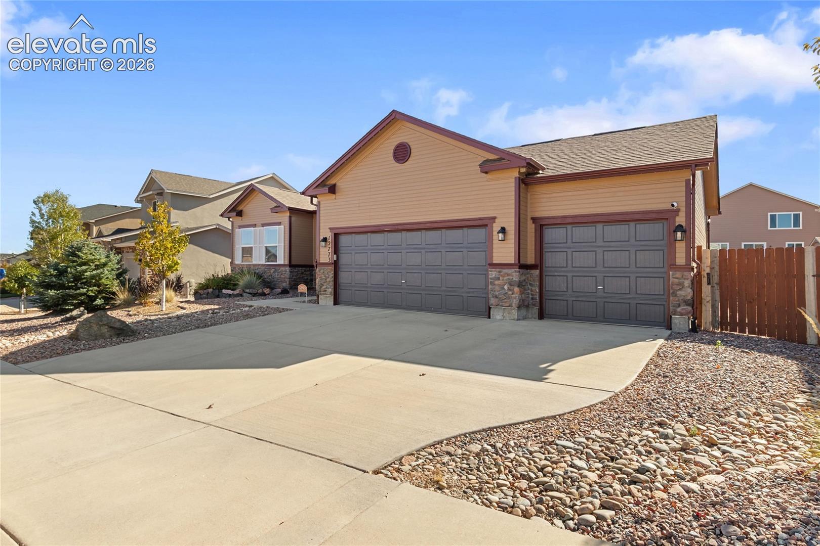 Exterior featuring horizontal siding, stone veneer accents, a three-car garage, and a concrete driveway