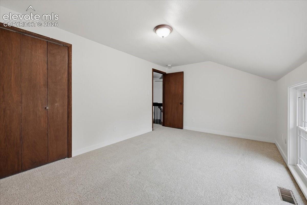 Bedroom 4 - Carpeted room featuring a ceiling-mounted light fixture, sloped ceiling detail, and a window overlooking the front yard