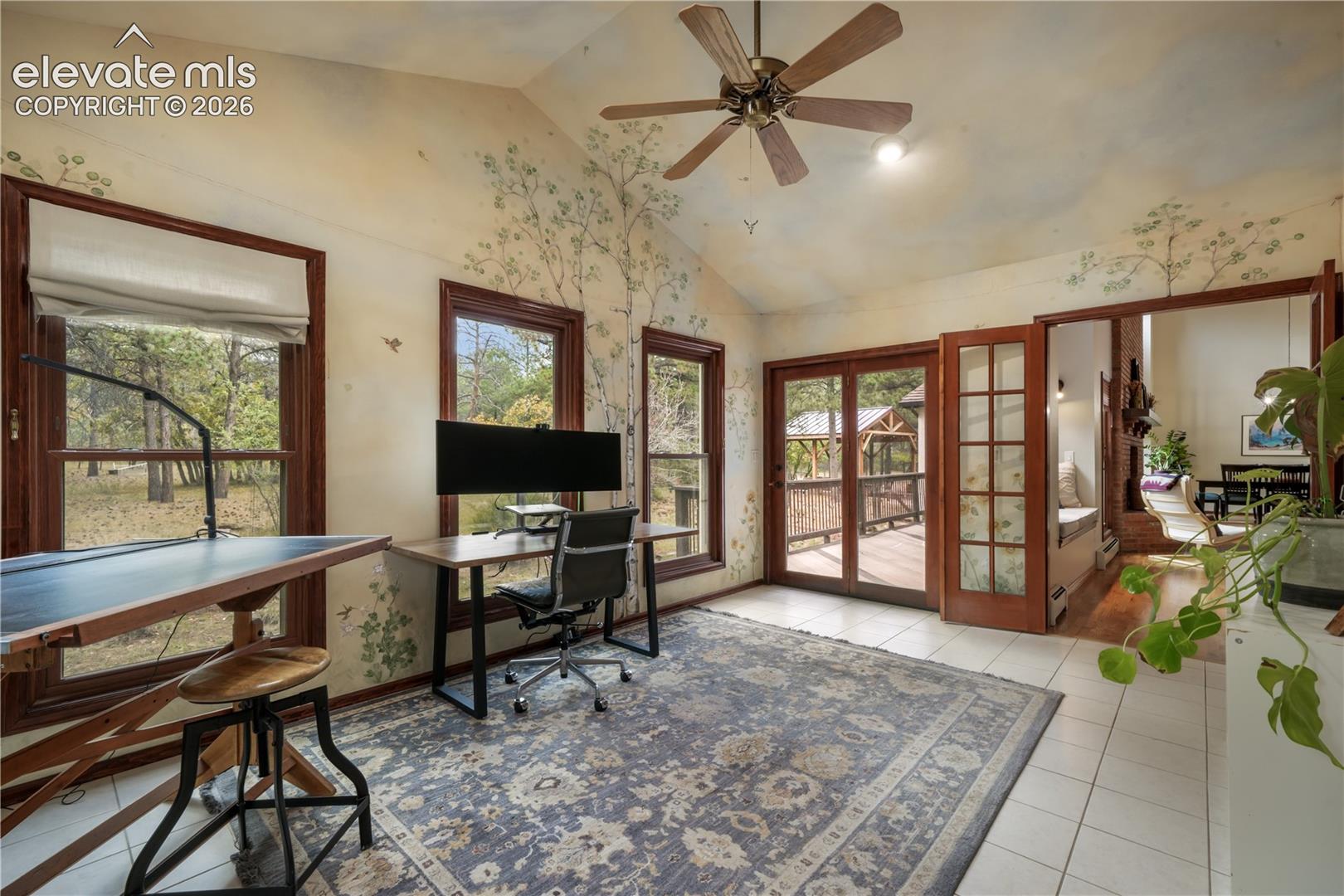 Main level office with glass french doors, tile flooring, vaulted ceilings and skylights