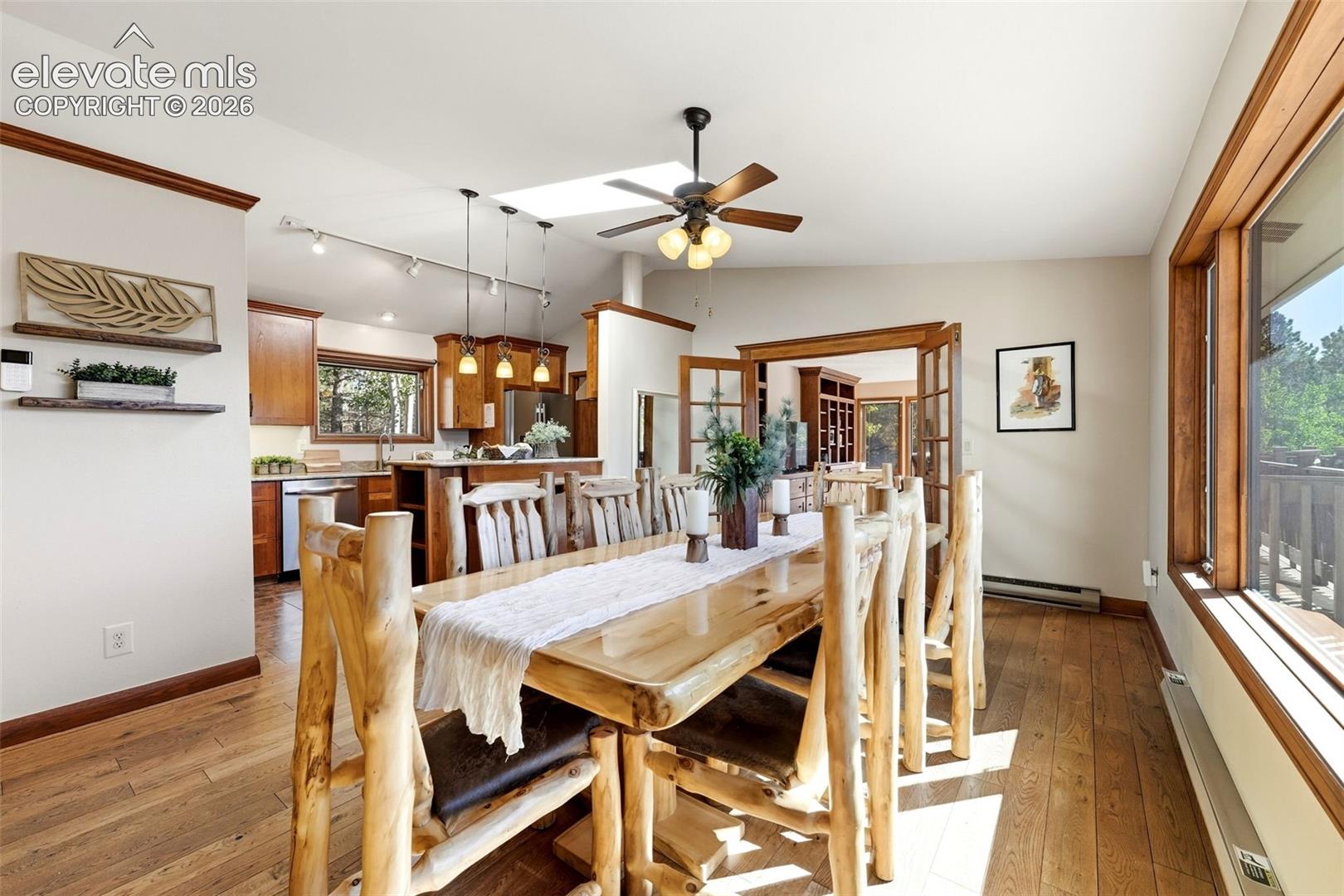 Wood-finish flooring, recessed lighting, and a skylight illuminate the dining area, which features access to an outdoor area