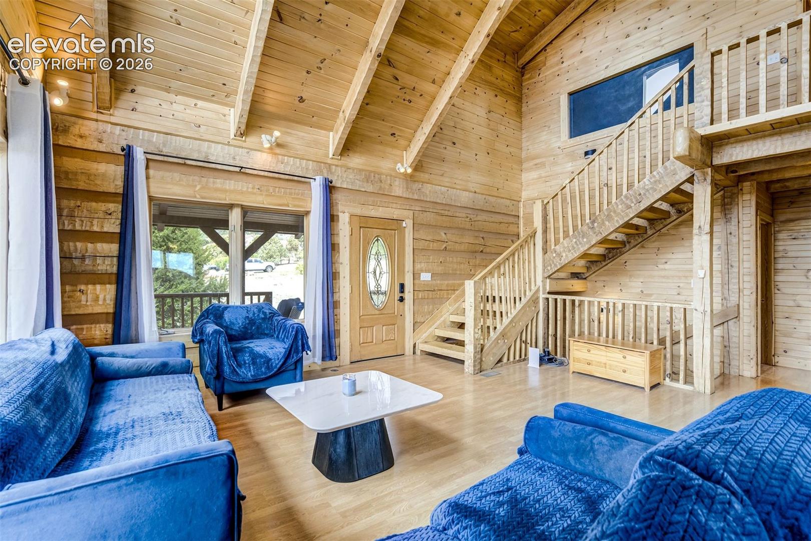 Vaulted wood-paneled ceiling with exposed beams, wood-finish flooring, and a prominent wood staircase with balusters