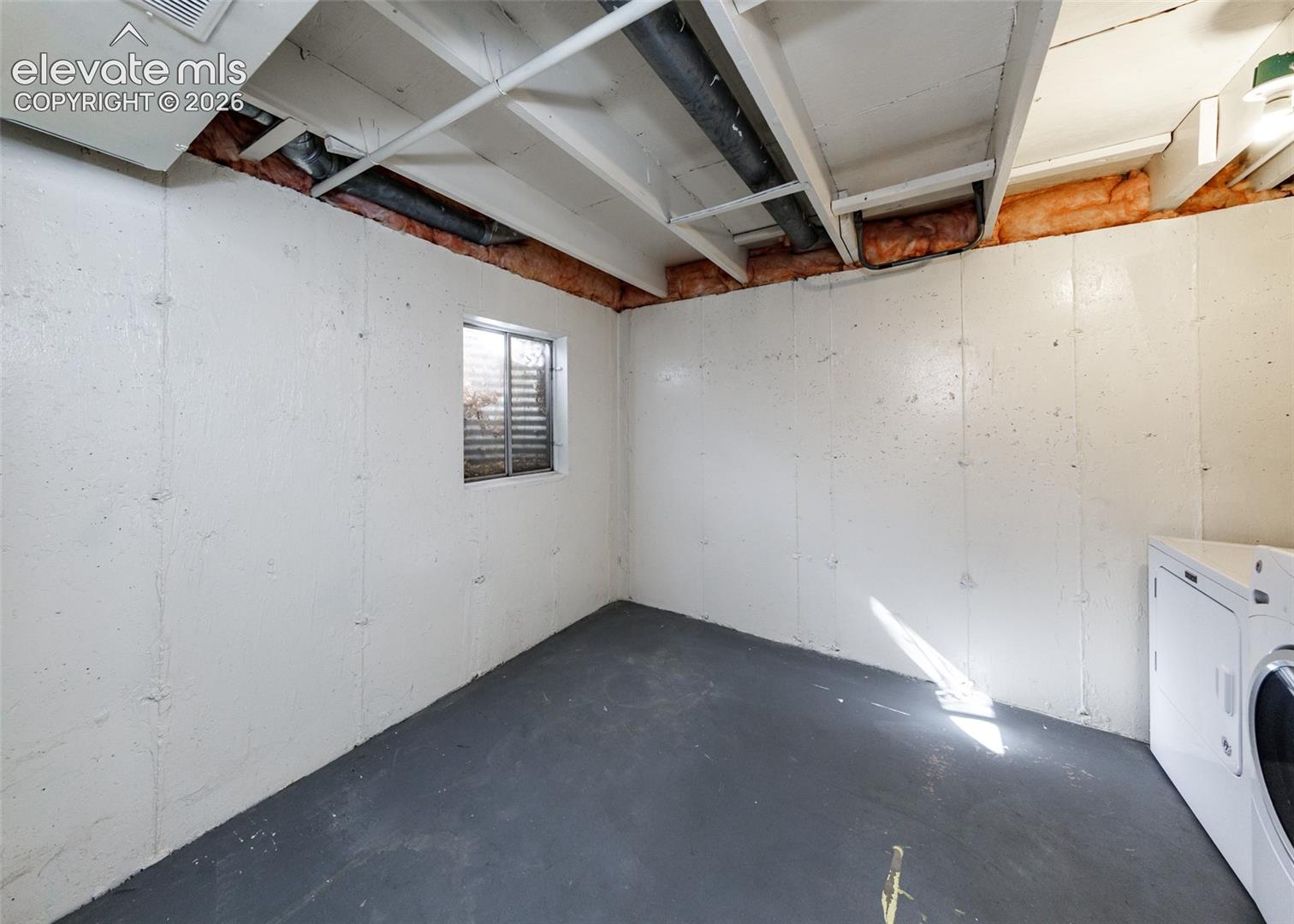 Finished concrete flooring, white painted masonry walls, exposed ceiling joists, and a casement window