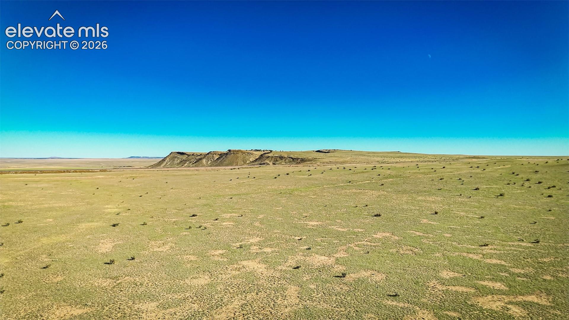 Expansive acreage featuring native grasses, arid terrain, and prominent mesa backdrop