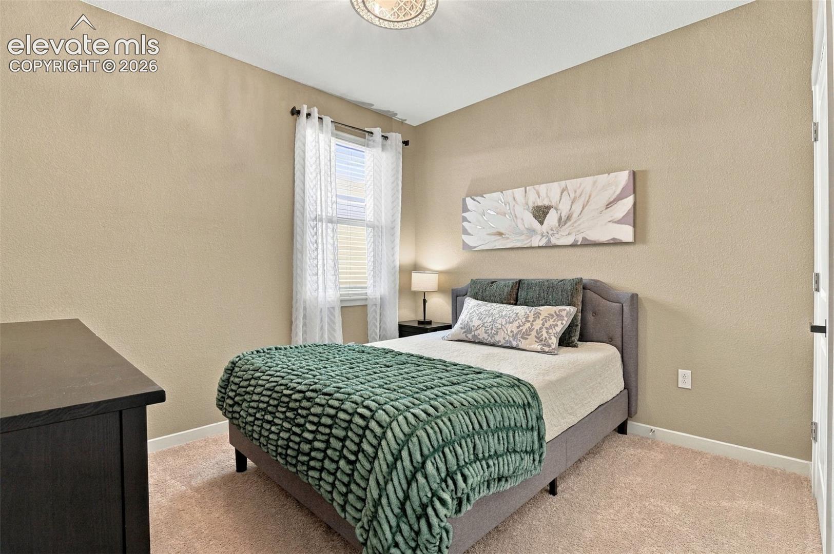 Neutral-toned room featuring wall-to-wall carpeting, textured wall finish, and a centered overhead flush-mount light fixture